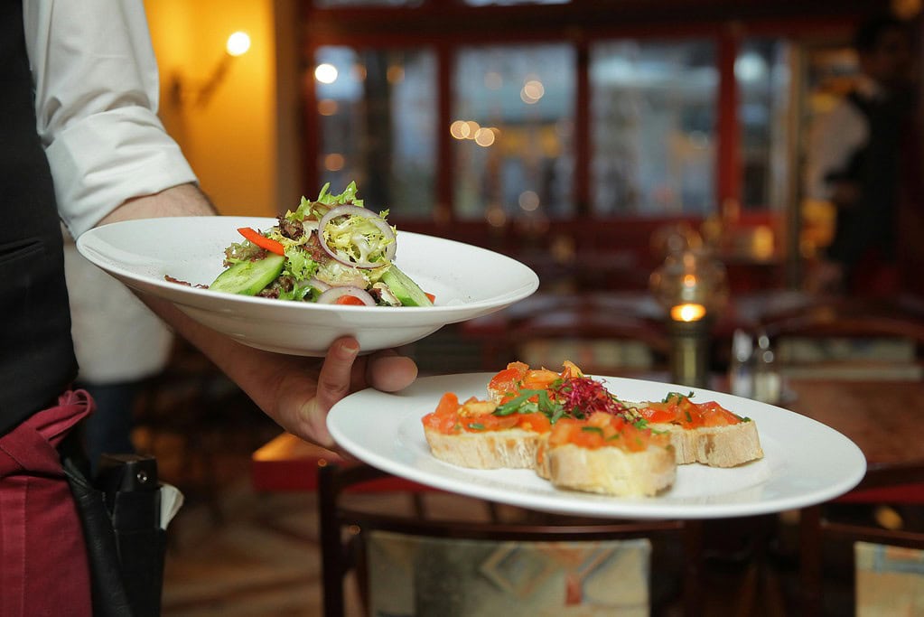A waiter serves a fresh salad and hors d'oeuvres in a restaurant 